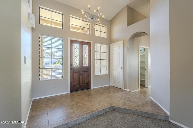 tiled entryway with a high ceiling and a notable chandelier