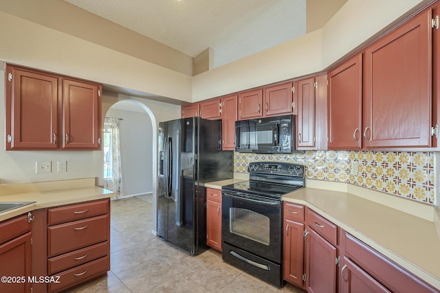 kitchen featuring a high ceiling, light tile patterned floors, black appliances, and tasteful backsplash