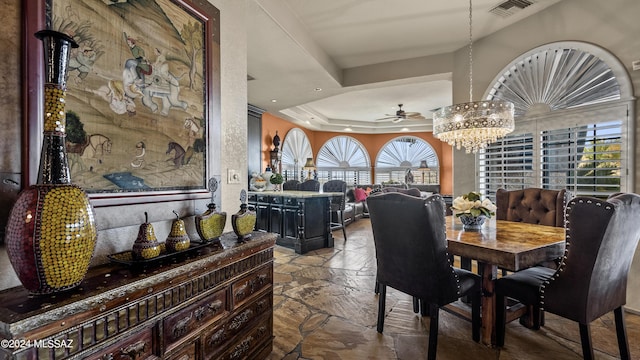 dining room featuring ceiling fan with notable chandelier, a raised ceiling, and a wealth of natural light