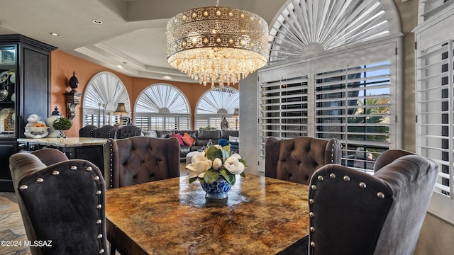 dining area featuring a raised ceiling and a chandelier