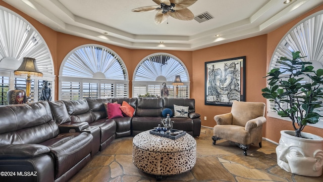 living room with ceiling fan and a tray ceiling