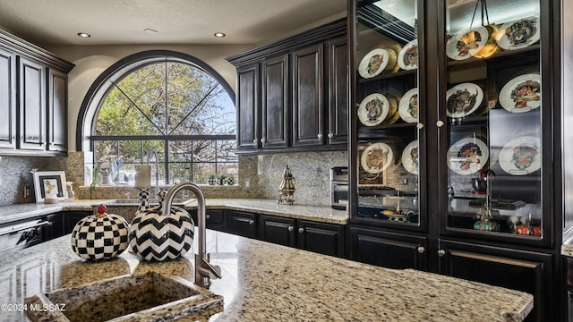 kitchen with backsplash, light stone counters, and sink