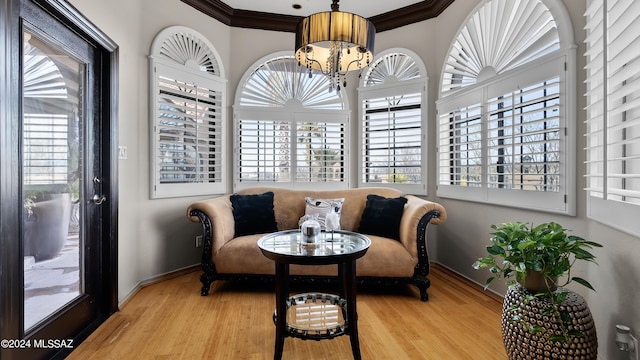 sitting room featuring light wood-type flooring, an inviting chandelier, and ornamental molding