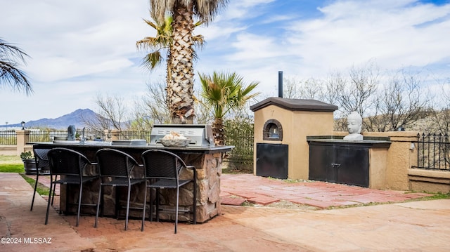 view of patio featuring a mountain view, exterior bar, and an outdoor kitchen