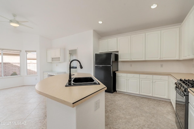 kitchen with white cabinets, a center island with sink, black appliances, and sink