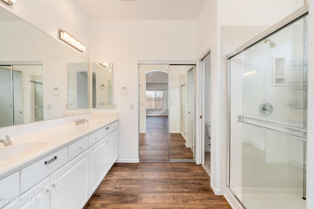 bathroom with toilet, wood-type flooring, vanity, and an enclosed shower