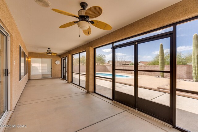 unfurnished sunroom featuring ceiling fan