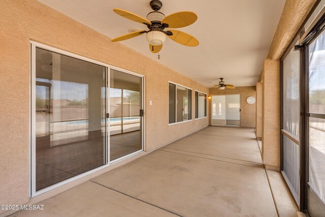 unfurnished sunroom featuring ceiling fan and a wealth of natural light