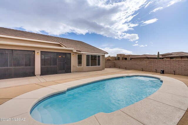 back of property with a fenced in pool, a patio area, and a sunroom