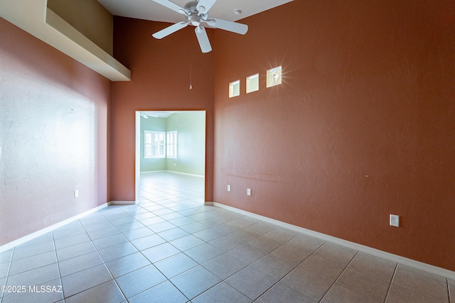 tiled empty room featuring a towering ceiling and ceiling fan