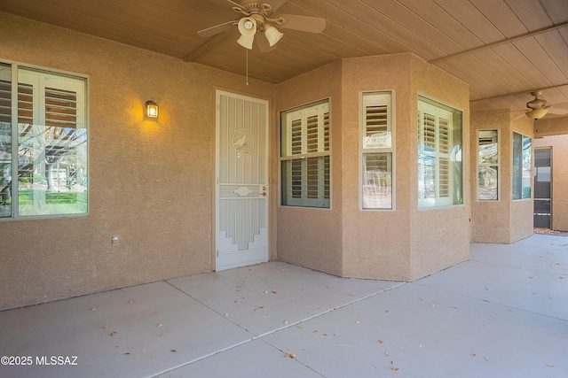 view of exterior entry with ceiling fan and a patio area