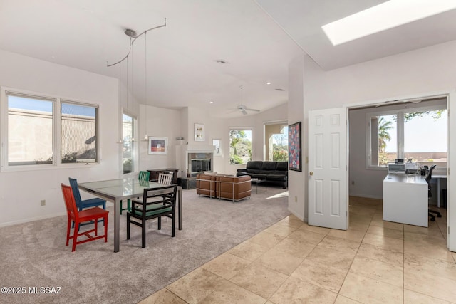 carpeted dining room with ceiling fan, plenty of natural light, and lofted ceiling with skylight