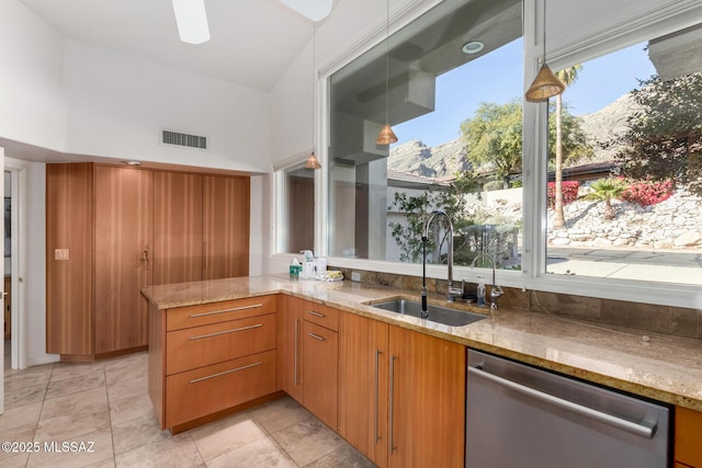 kitchen featuring stainless steel dishwasher, kitchen peninsula, sink, a mountain view, and light stone countertops