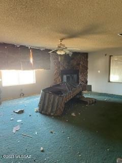 interior space featuring a fireplace, a textured ceiling, and ceiling fan