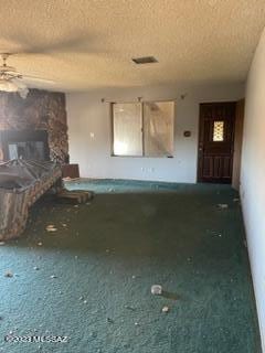 interior space featuring a fireplace, a textured ceiling, and ceiling fan