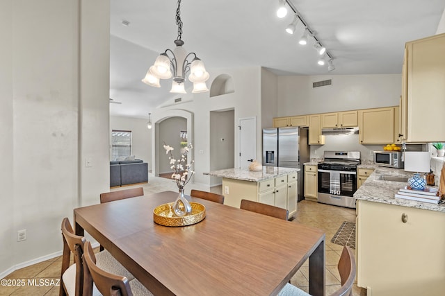 tiled dining space with an inviting chandelier, track lighting, and high vaulted ceiling