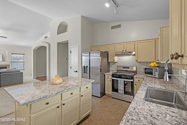 kitchen featuring light tile patterned flooring, appliances with stainless steel finishes, a center island, and light stone counters