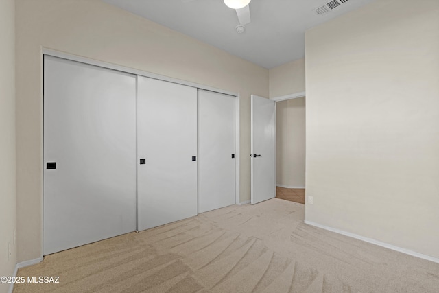 unfurnished bedroom featuring light colored carpet, ceiling fan, and a closet