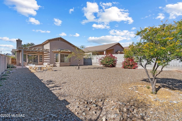 rear view of property featuring a pergola and a patio area