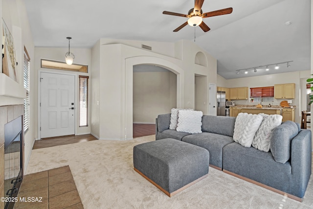 living room with rail lighting, lofted ceiling, light colored carpet, and ceiling fan