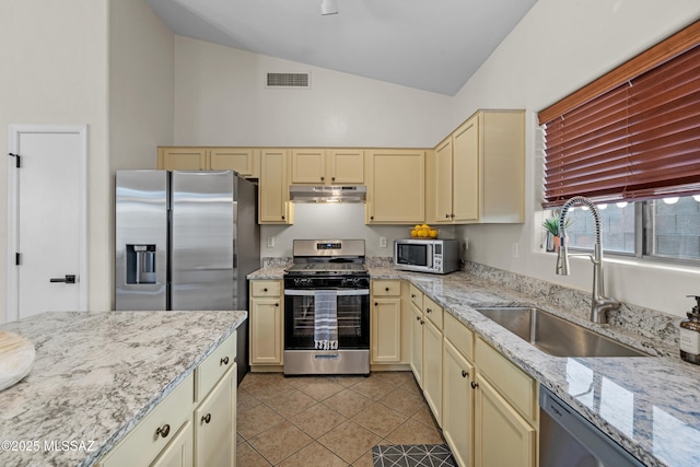 kitchen with lofted ceiling, sink, stainless steel appliances, and cream cabinetry