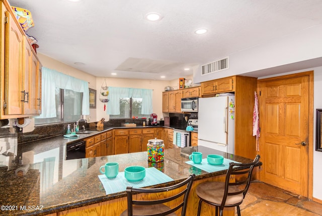 kitchen featuring dishwasher, a kitchen breakfast bar, kitchen peninsula, white fridge, and electric stove