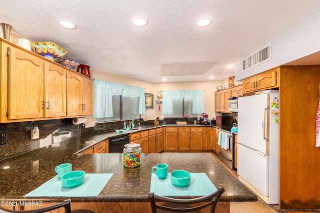 kitchen with a textured ceiling, kitchen peninsula, sink, and white appliances