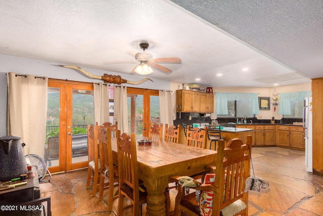 dining room featuring ceiling fan, french doors, a textured ceiling, and sink