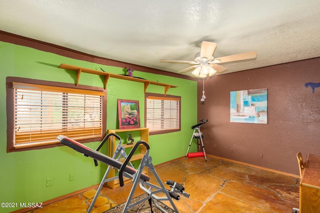 workout room featuring ceiling fan and a textured ceiling