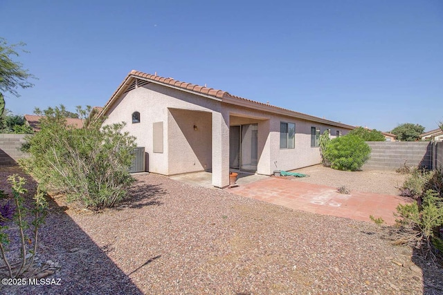 back of property with a fenced backyard, a tiled roof, stucco siding, and a patio