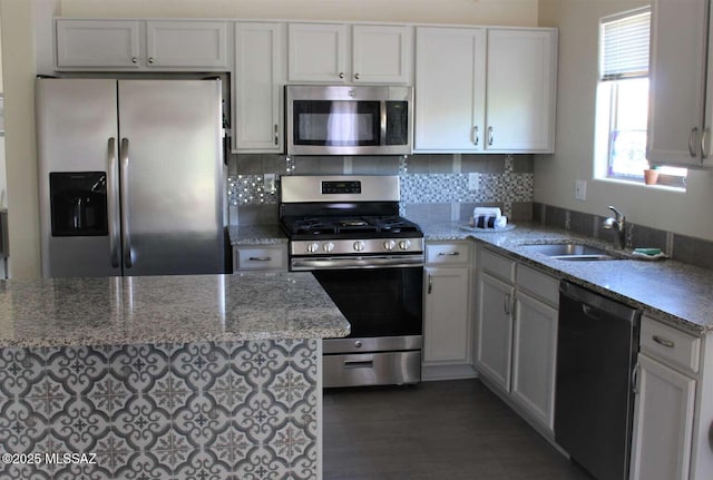 kitchen featuring light stone counters, a sink, white cabinetry, appliances with stainless steel finishes, and decorative backsplash