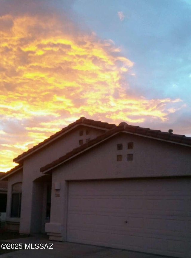 view of front facade featuring a tile roof, stucco siding, an attached garage, and concrete driveway