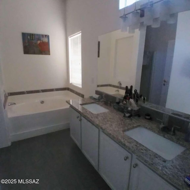 bathroom with double vanity, a bath, and a sink