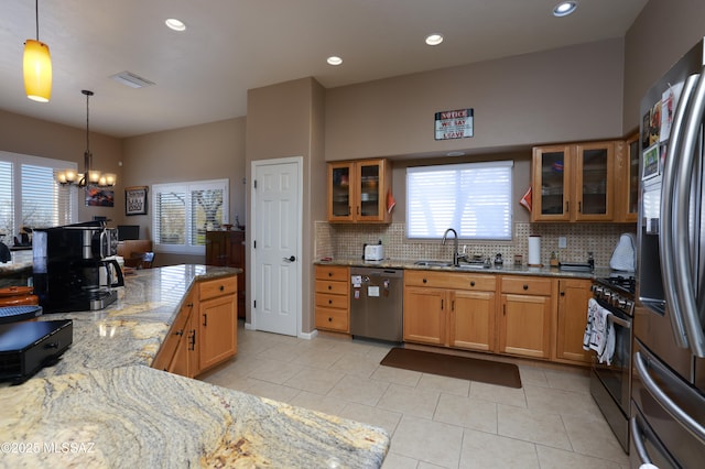 kitchen featuring sink, decorative light fixtures, light stone counters, stainless steel appliances, and a chandelier