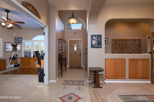 foyer with ceiling fan, light tile patterned floors, and a high ceiling