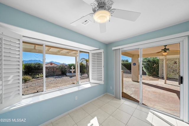 empty room with a mountain view, light tile patterned floors, and ceiling fan