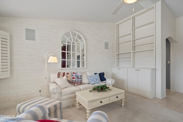 living room with ceiling fan, brick wall, light tile patterned floors, and lofted ceiling