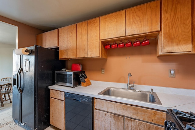 kitchen featuring black appliances, light countertops, and a sink