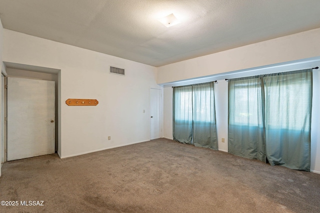 unfurnished bedroom featuring visible vents, a textured ceiling, and carpet flooring