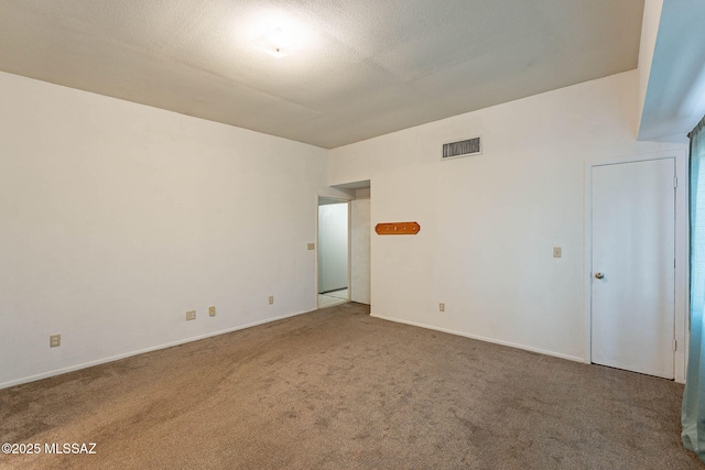 spare room featuring carpet flooring, visible vents, and baseboards