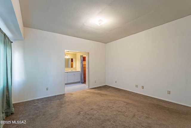 carpeted spare room featuring a textured ceiling and baseboards