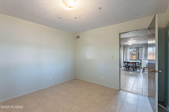 empty room featuring visible vents, a textured ceiling, baseboards, and light tile patterned flooring