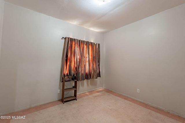 spare room with baseboards and light floors