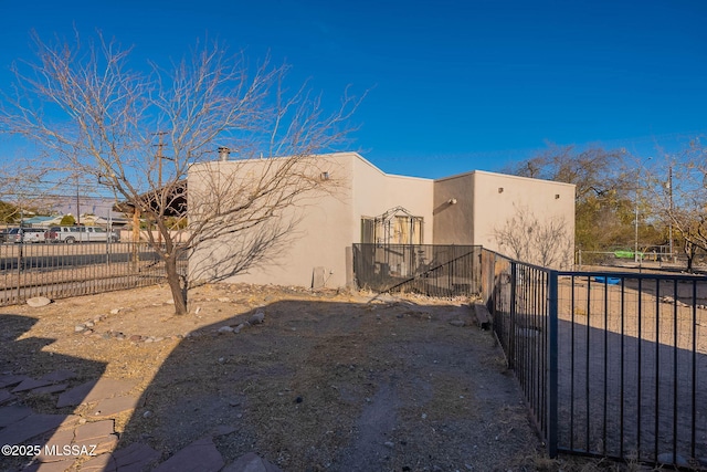 view of side of property with fence and stucco siding