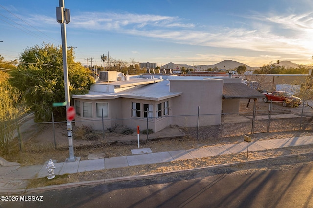 view of front of property with a fenced front yard, a mountain view, and stucco siding