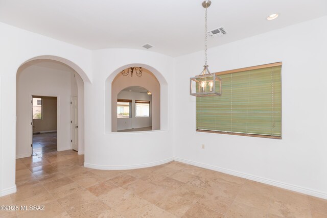 spare room featuring ceiling fan with notable chandelier