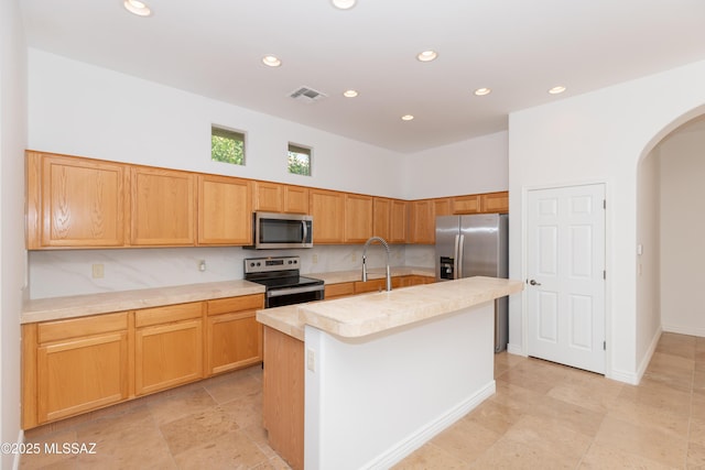 kitchen with stainless steel appliances, a kitchen island with sink, and sink