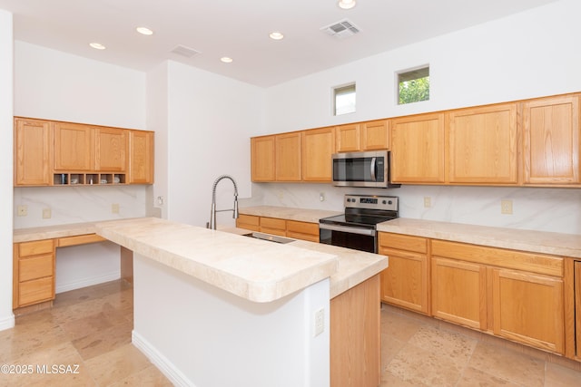 kitchen with appliances with stainless steel finishes, an island with sink, a towering ceiling, and sink