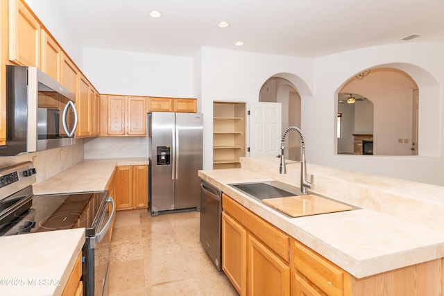 kitchen featuring sink, stainless steel appliances, a kitchen island, ceiling fan, and light brown cabinets