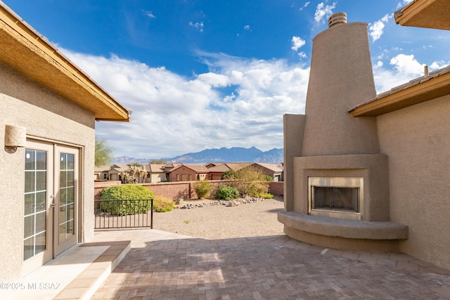 view of patio / terrace with french doors, exterior fireplace, and a mountain view